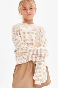 A girl wearing a cream and taupe fine horizontal stripe brushed knit pullover top with a crew neckline, long sleeves with slightly flared cuffs, and a relaxed fit.