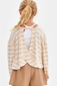 A girl wearing a cream and taupe fine horizontal stripe brushed knit pullover top with a crew neckline, long sleeves with slightly flared cuffs, and a relaxed fit.